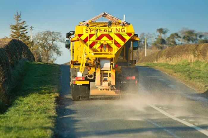 Road maintenance vehicle spreading material on the road surface.