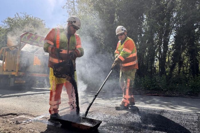Highways crew patching a pothole on a dry road surface.