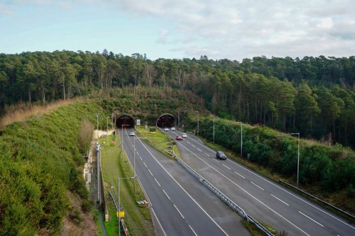 Aerial view of the twin tunnel entrances at the Hindhead Tunnel on the A3, surrounded by woodland.